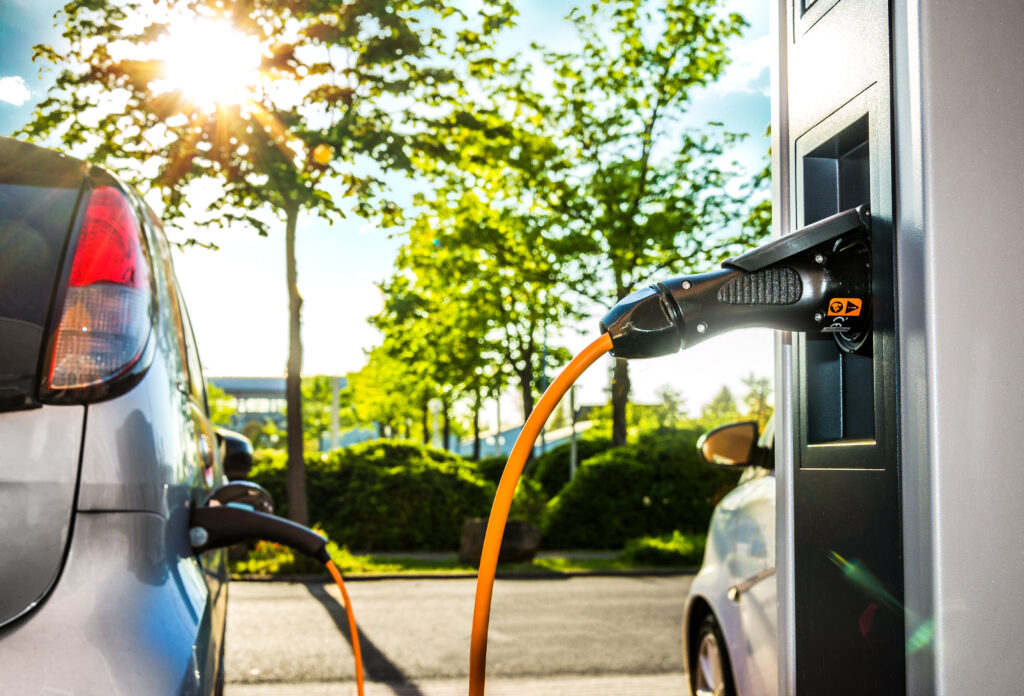 Elektroautos an Ladestation auf Firmengelände im Gegenlicht –